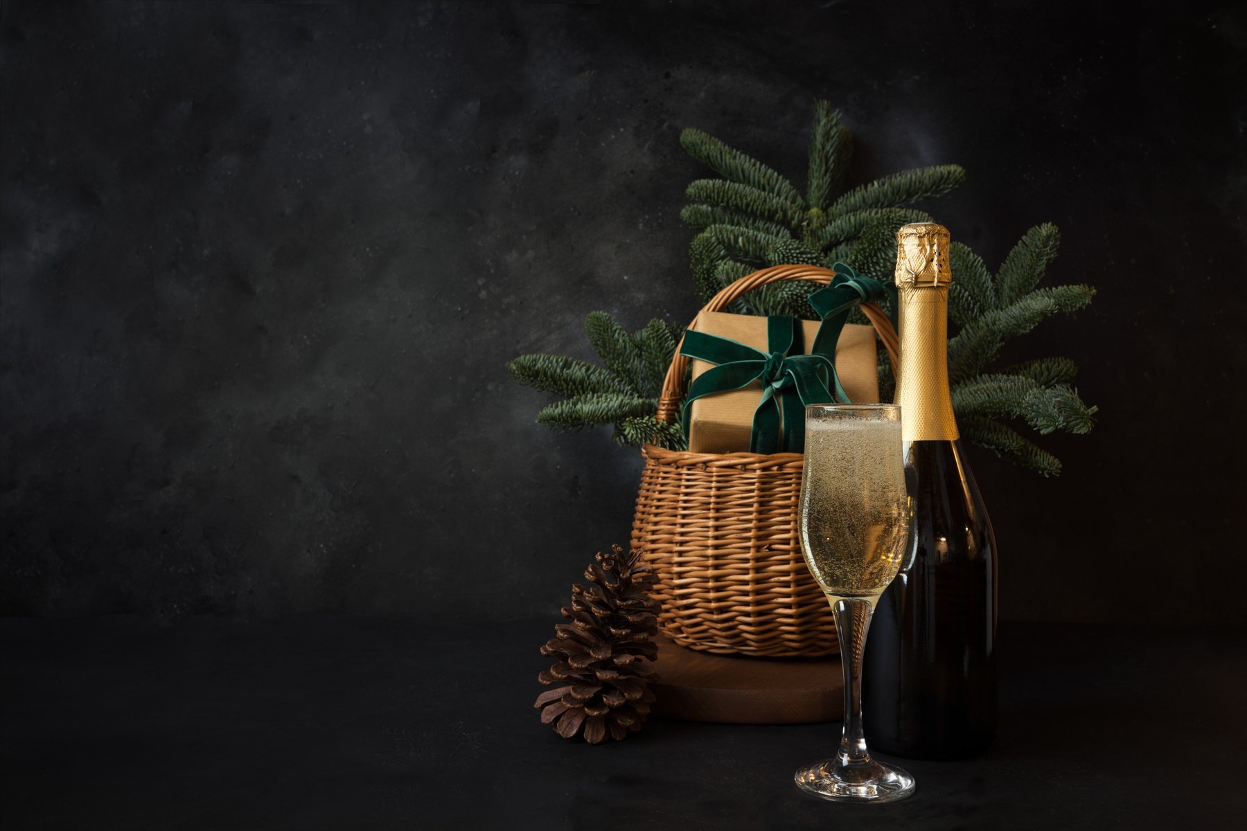 Christmas Holiday Hamper with Glass of Sparkling Wine and Gift on Black.